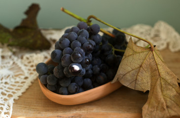 Grapes in a clay plate on a wooden background. Rustic style, selective focus.