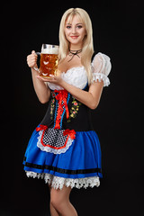 Young sexy woman wearing a dirndl with beer mug on black background.