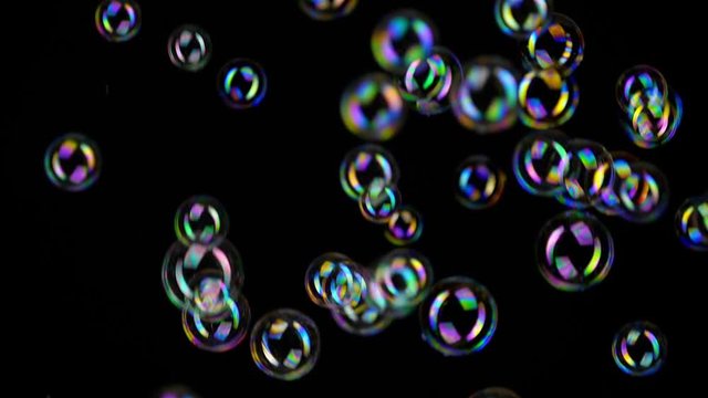 Colorful soap bubbles fly across black background.
