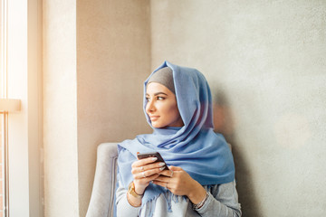Muslim woman messaging on a mobile phone in cafe