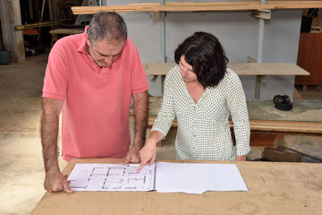 woman looking at the blueprints of a project in the carpenter's workshop