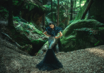 Girl - black raven wanders in the mountains. Gothic photosession theme of Halloween. Unusual, creative outfit