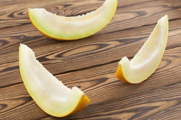 Three slices of fresh ripe yummy melon on old rustic brown wooden background