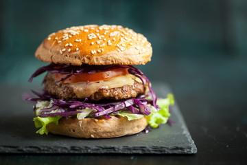 Burger with purple cabbage over black textured board 