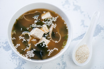 Bowl of hot miso soup on a white concrete background, high angle view, horizontal shot