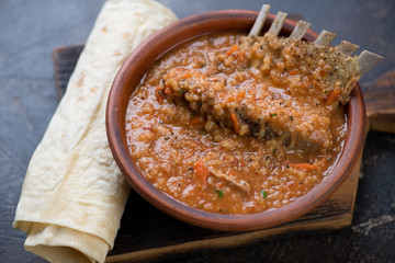 Kharcho soup with lamb meat served in a clay bowl with lavash flatbread, studio shot
