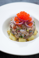 Close-up of herring tartare with red onion and red caviar topping, vertical shot