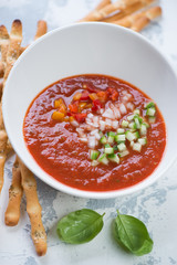 Cold gazpacho soup with grissini and fresh green basil, vertical shot