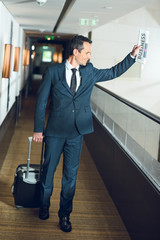 businessman walking in hotel corridor with suitcase