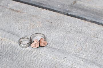 Obraz na płótnie Canvas wedding rings with wooden hearts showing love