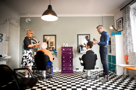 Couple in vintage clothes working on customers in quirky hair salon