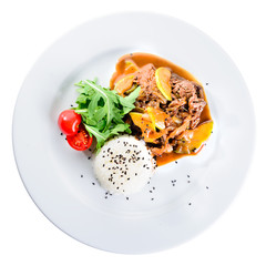 Delicious beef with oyster Mushrooms and rice served with tomatoes and sauce in a white plate isolated on white background. Autumn menu in an Italian restaurant. Top view, flat, overhead