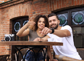 Happy couple drinking coffee in outdoors cafe on summer vacation