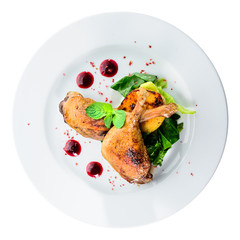 Juicy delicious cooked duck legs served with herbs and sauce in a white plate isolated on black background. Autumn menu in an Italian restaurant. Top view, flat, overhead