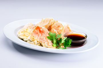 Delicious and appetizing tempura-fried vegetables served with soy sauce in a white plate on light background. Autumn menu in an Italian restaurant