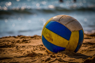 Volleyball on yellow sand on empty beach in twilight