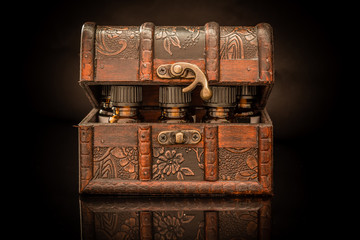 Bottles of tincture or potion in a retro styled.old treasure chest on black background