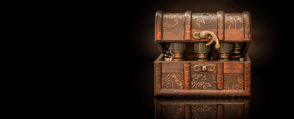 Bottles of tincture or potion in a retro styled.old treasure chest on black background