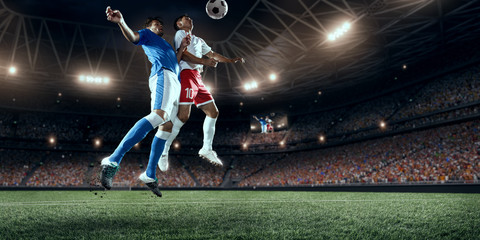 Soccer players performs an action play on a professional stadium. Two football teams fighting for...