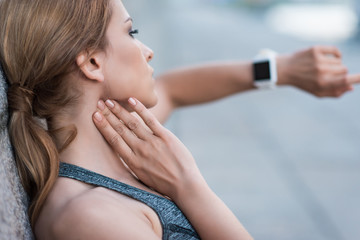 sportswoman measuring pulse with smartwatches