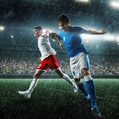 Fototapeta na wymiar Soccer players performs an action play on a professional rainy stadium. Two football teams fighting for the ball. Players wears unbranded sport uniform.