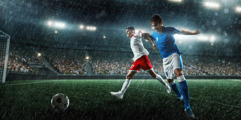 Soccer players performs an action play on a professional rainy stadium. Two football teams fighting...