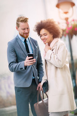 Happy business couple using smart phone outdoors