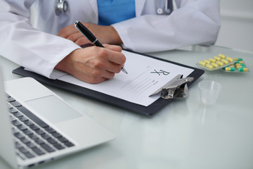 Doctor woman filling up prescription, close-up of hands. Physician at work. Medicine and healthcare concept