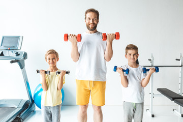 father and sons exercising with dumbbells