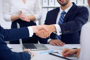 Business handshake at meeting or negotiation in the office, close-up. Partners are satisfied because signing contract or financial papers