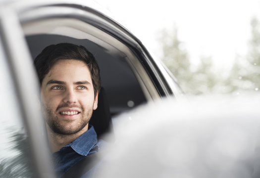 Portrait Of Smiling Young Man Driving Car In Winter