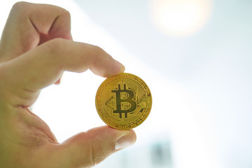 Fototapeta na wymiar man's hand holding golden Bitcoin on Bitcoin mining background