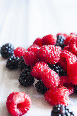 Fresh raspberries and blackberries on marble table, selective focus