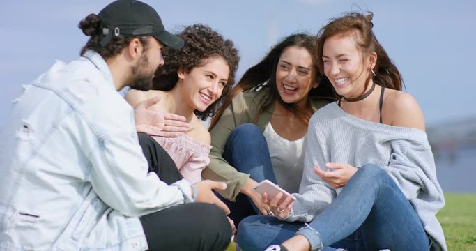 Multiethnic group of young people outside having fun with smartphone