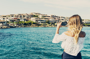 Fototapeta na wymiar Tourist woman taking photos of the sea with her smartphone