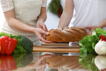 Close-up of human hands slicing bread in a kitchen. Friends having fun while cooking in the kitchen. Chef cook represent culinary masterclass