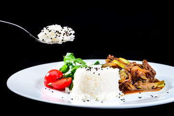 Process of eating delicious beef with oyster Mushrooms and rice served with tomatoes and sauce in a white plate on black background. Autumn menu in an Italian restaurant.