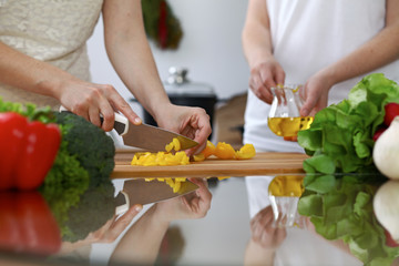 Close-up of  human hands  cooking in a kitchen. Friends having fun while preparing fresh salad. Vegetarian, healthy meal and friendship concept