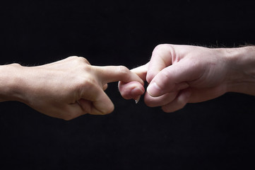 Male and female hands together on black background