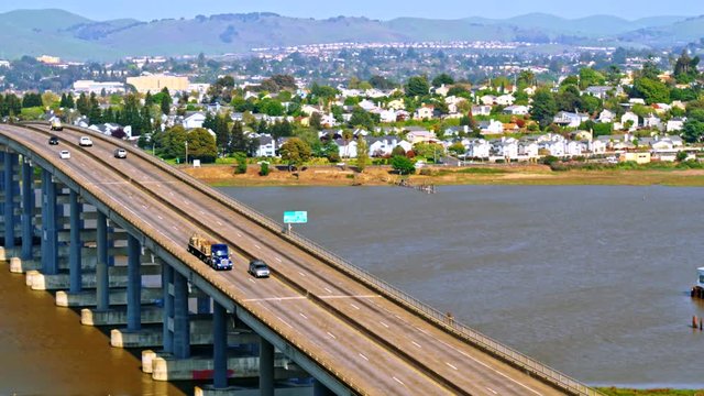 Truck with hauling cargo crossing over Napa river bridge with light traffic near Vallejo, California with city in the background