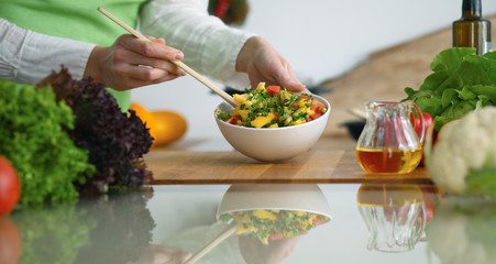 Closeup of human hands cooking vegetables salad in kitchen on the glass  table with reflection