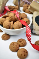 Traditional Dutch pepernoten or cinnamon spiced cookies displayed in a white bowl and decorated with a festive bright red ribbon