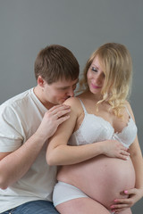 Beautiful pregnant couple in love on the background.Hands of husband on the tummy of his pregnant wife. Young man tenderly stroked pregnant belly of his wife. Husband kissing pregnant belly.