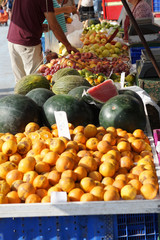 Fruits are spread out in the market on the counter, buyers choose the goods, ripe watermelons and melons