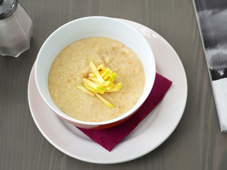 Oatmeal porridge with cut slices of apples in a deep plate on a wooden table. A good and useful diet breakfast for a healthy lifestyle