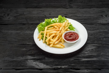 Fried potatoes with ketchup over dark wooden background