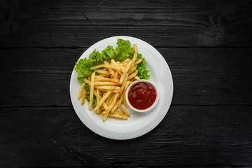 Fried potatoes with ketchup over dark wooden background