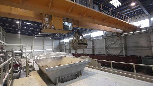 Work on the bridge crane stock granulation of bulk materials, Warehouses for bulk materials, Grab crane loads raw materials, crane bucket, Modern factory, interior