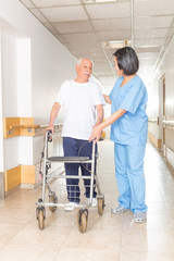 Obraz premium Nurse helping elderly man with walker in hospital