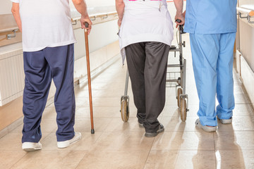 Elderly man with walker and walking stick in hospital rehab